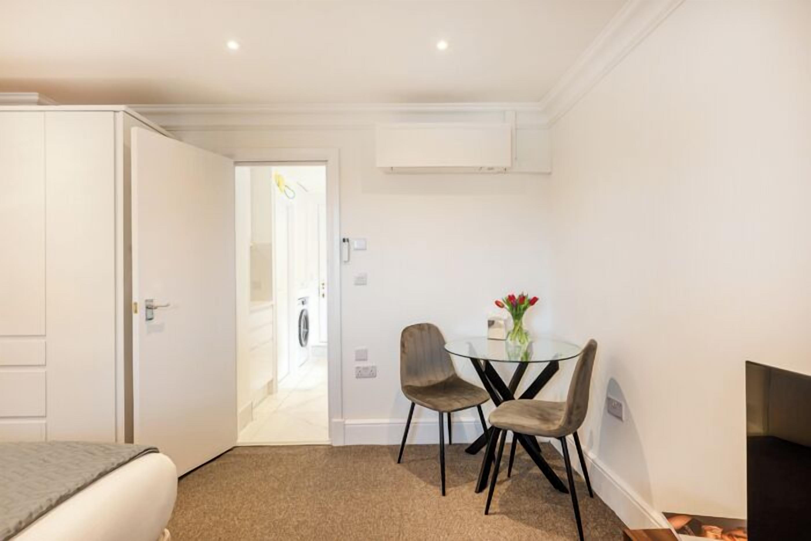 Une chambre d’h ôtel avec un lit, une petite table et des chaises, une télévision et une porte donnant sur un couloir.