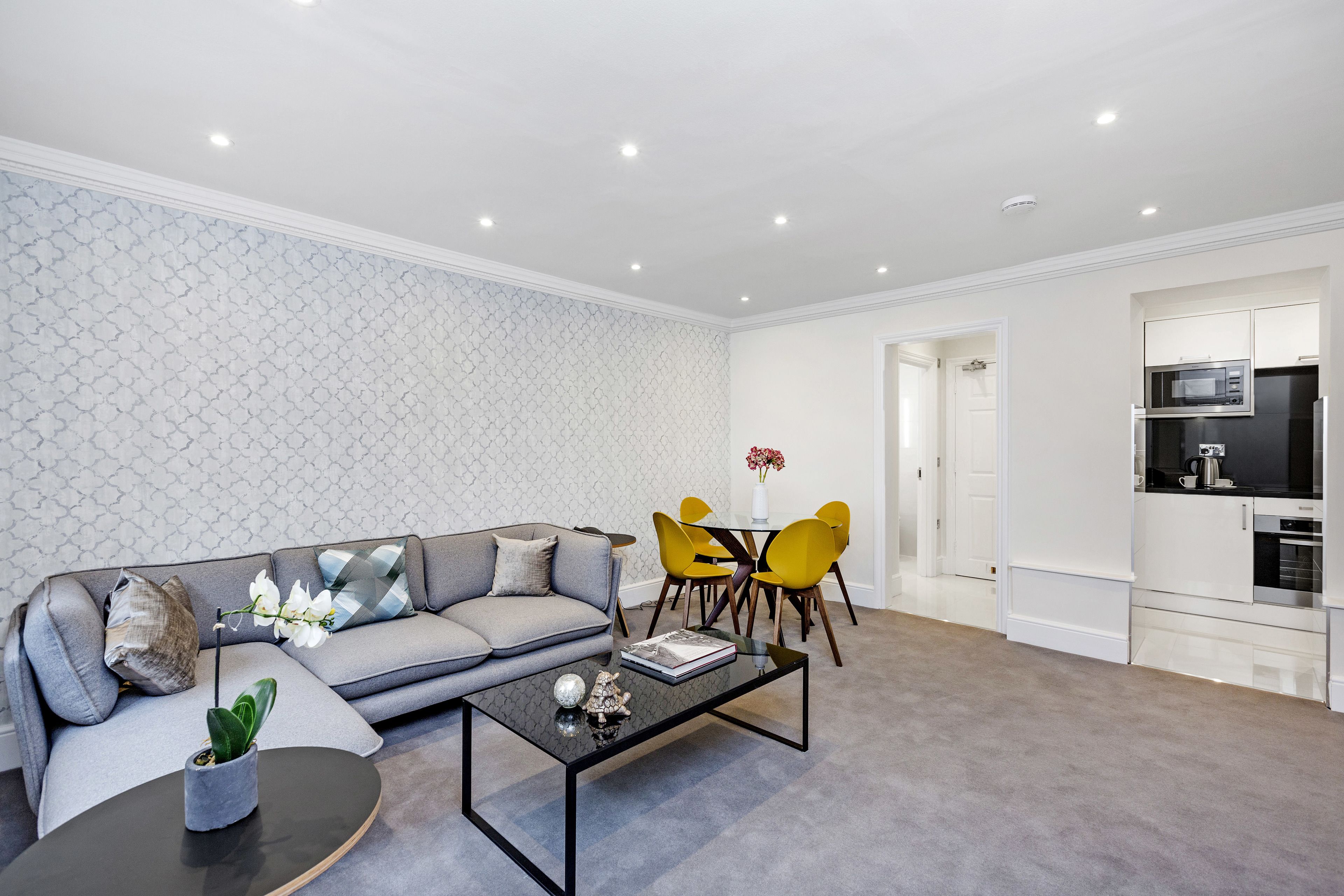 Un salon moderne avec un canapé gris, une table basse et des chaises jaunes.