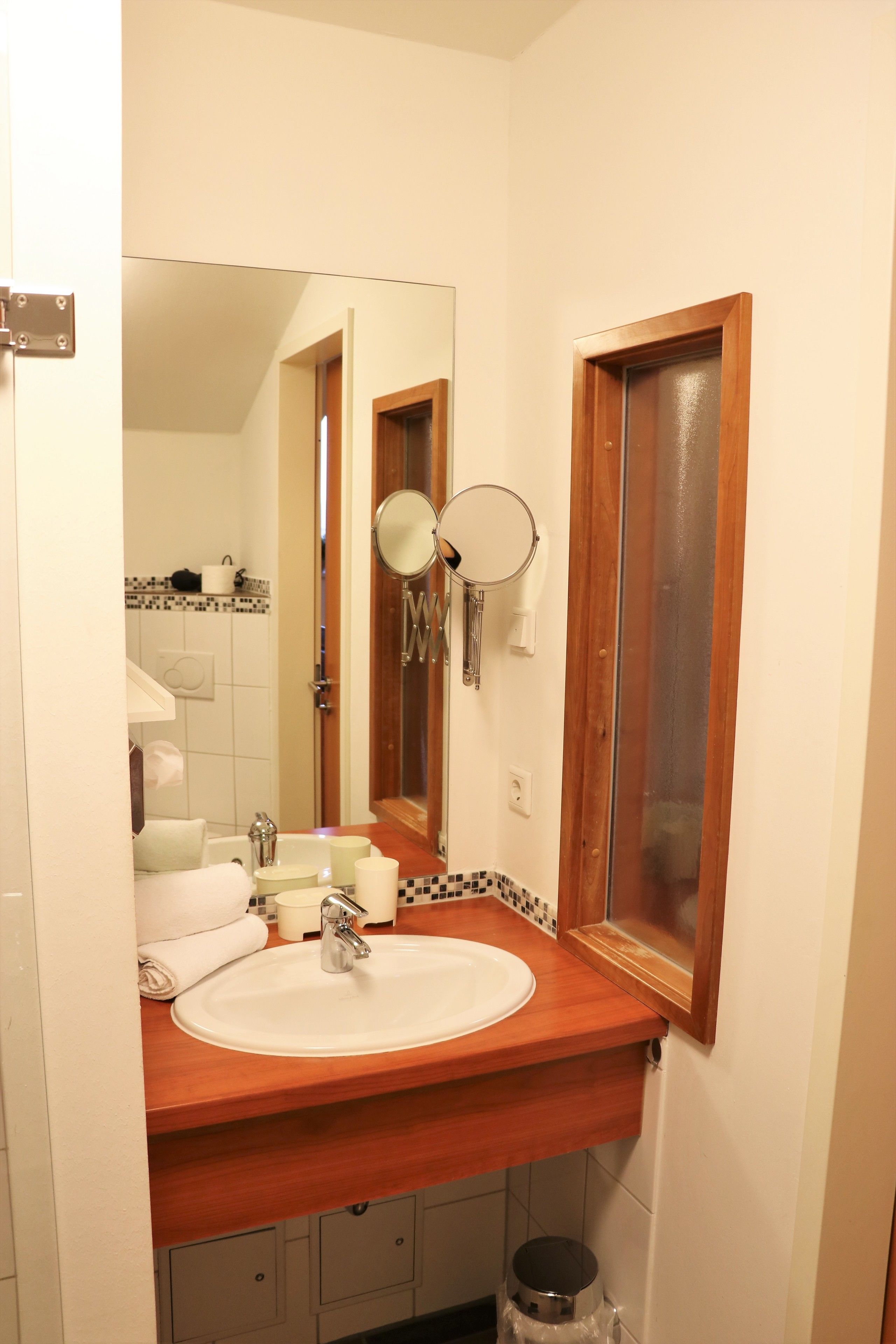 A bathroom with a wooden vanity, a sink, a mirror, and a toilet.