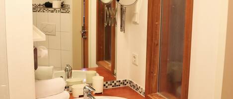 A bathroom with a wooden vanity, a sink, a mirror, and a toilet.
