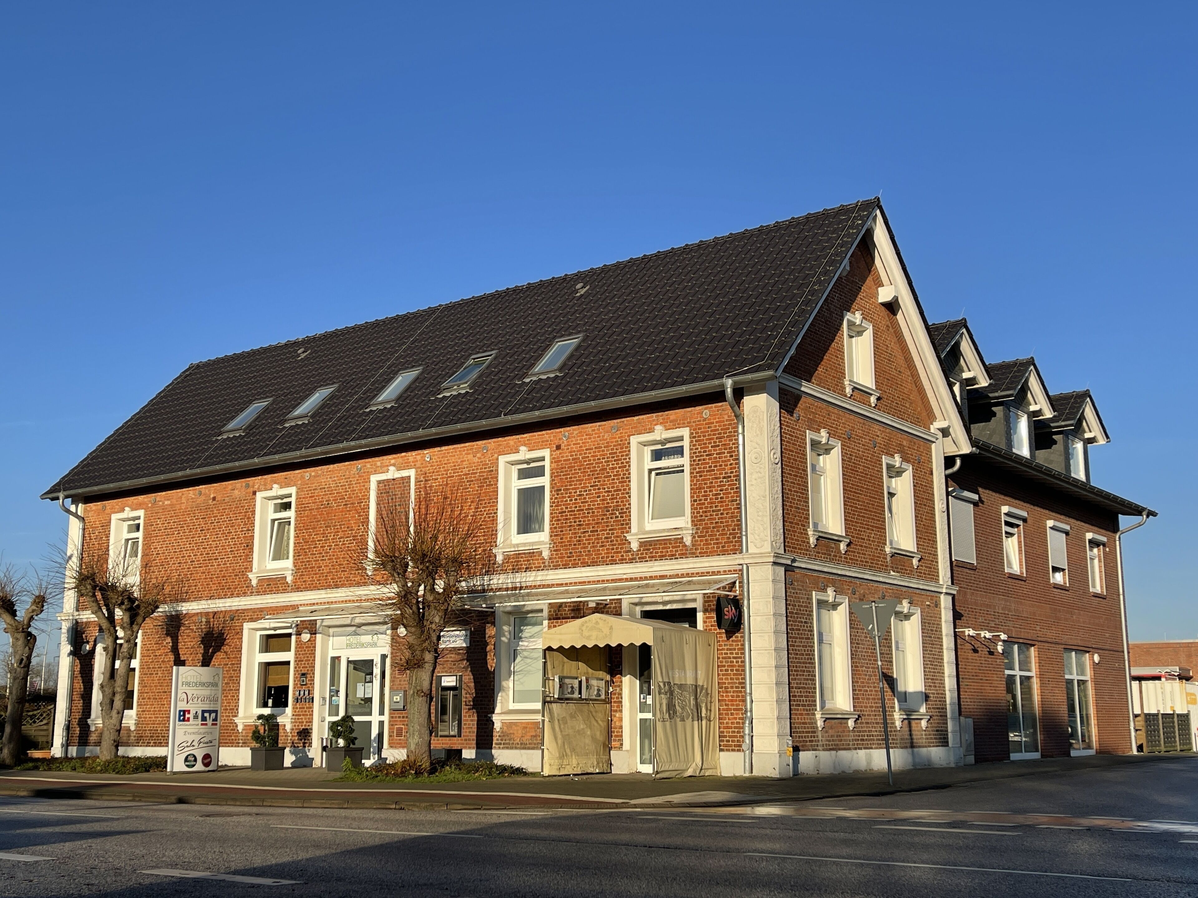A two-story brick building with a gabled roof, multiple windows, and a sign indicating it is a hotel.