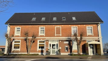 A two-story brick building with a dark tiled roof, multiple windows, and a central entrance.