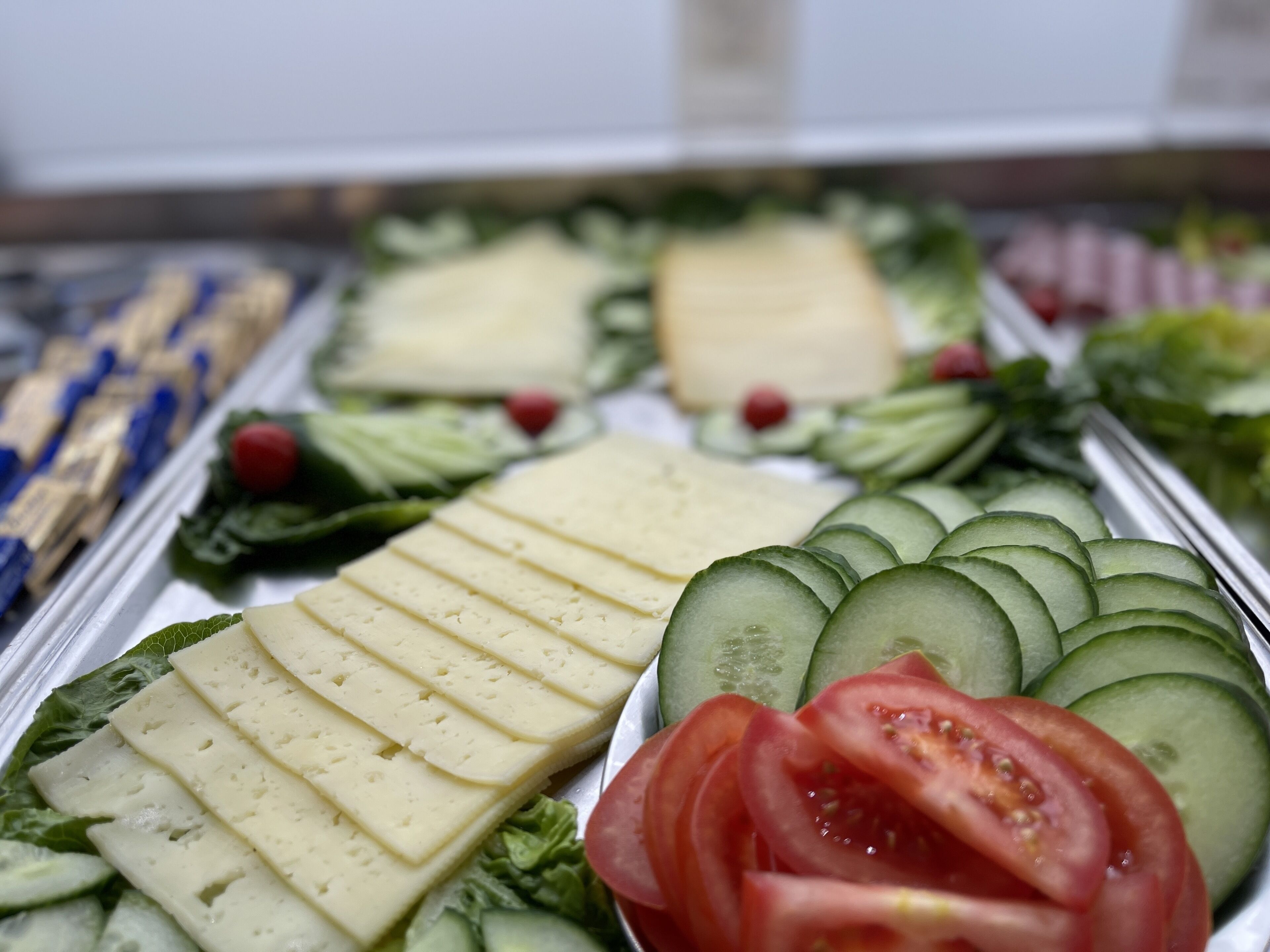 A display of cheese, cucumbers, and tomatoes.