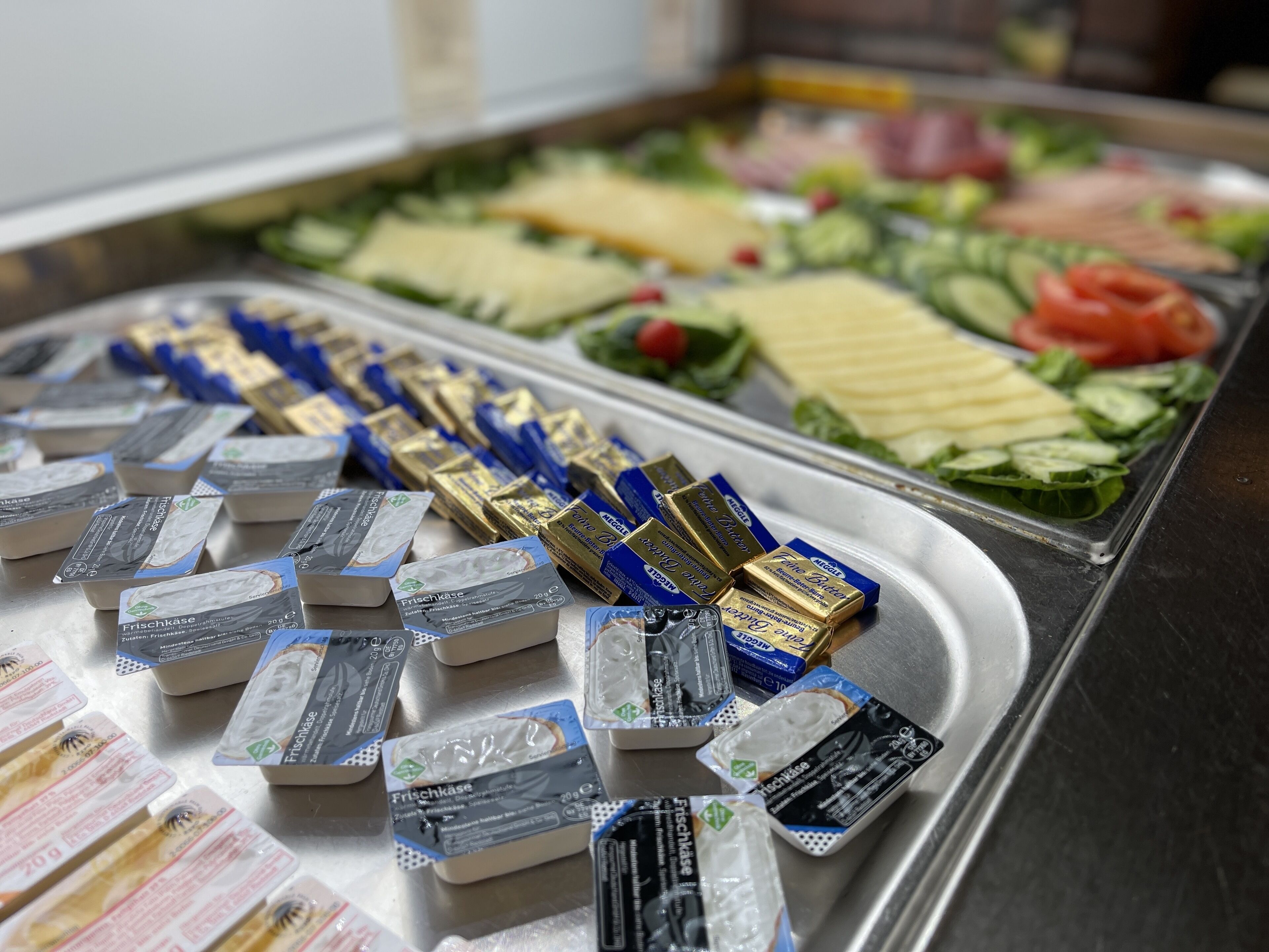 Een buffet met diverse gerechten, waaronder kaas, groenten en verpakte producten.
