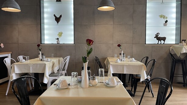 A restaurant with tables set for dining, featuring a modern interior with pendant lighting and decorative items on the walls. - Hotel Frederikspark (Norderstedt)
