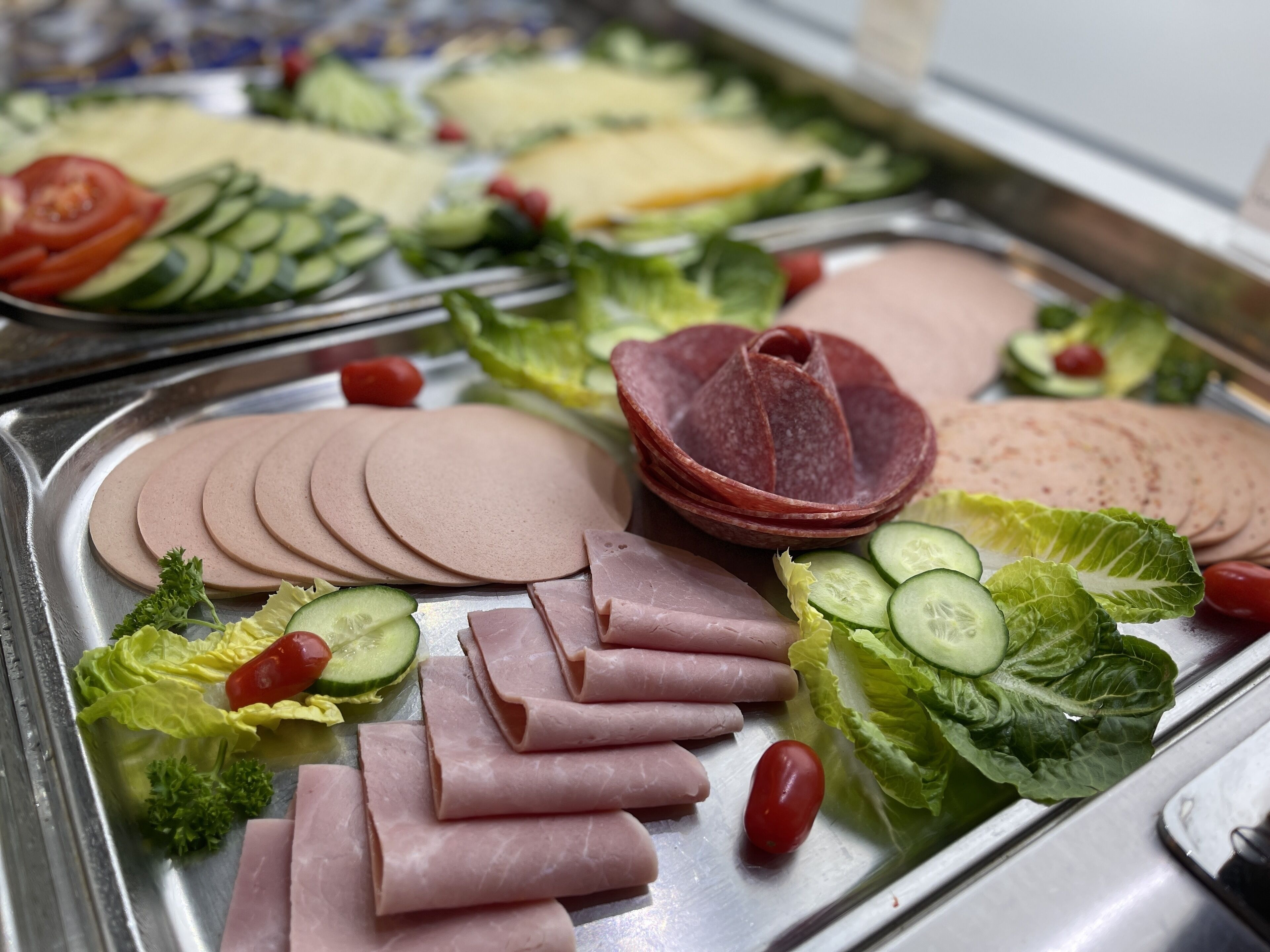 Ein reichhaltiges Buffet mit verschiedenen Wurstwaren, Käsesorten und frischem Gemüse.