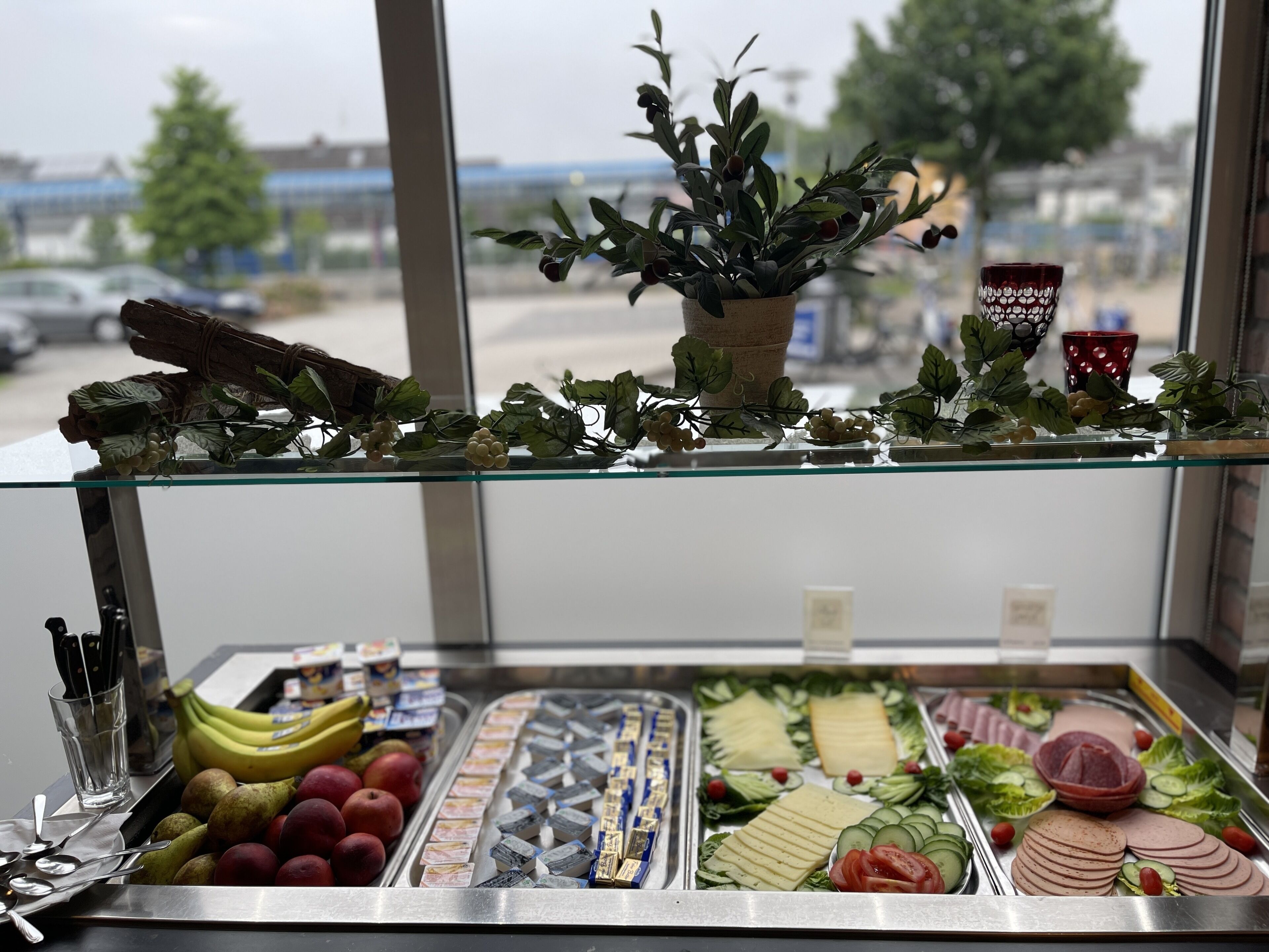 A glass display case with a variety of food items including fruits, cheeses, and deli slices.