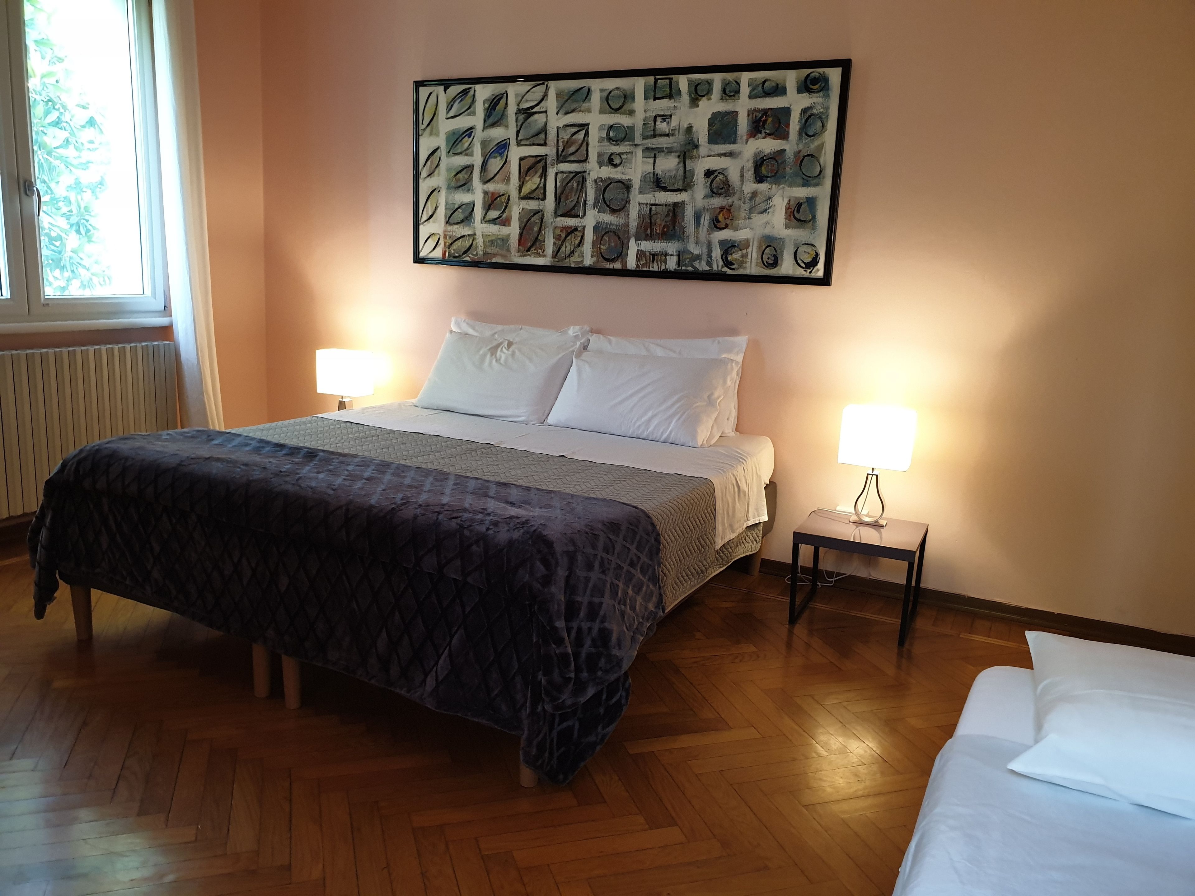 A neatly arranged bedroom with a bed, two bedside tables, and a wall-mounted artwork.