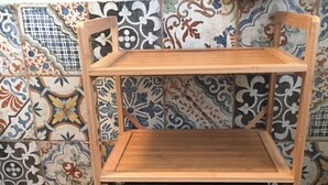 A wooden shelf unit with a top shelf and two drawers against a tiled wall. - B&B Villa al Parco (Sala Baganza)