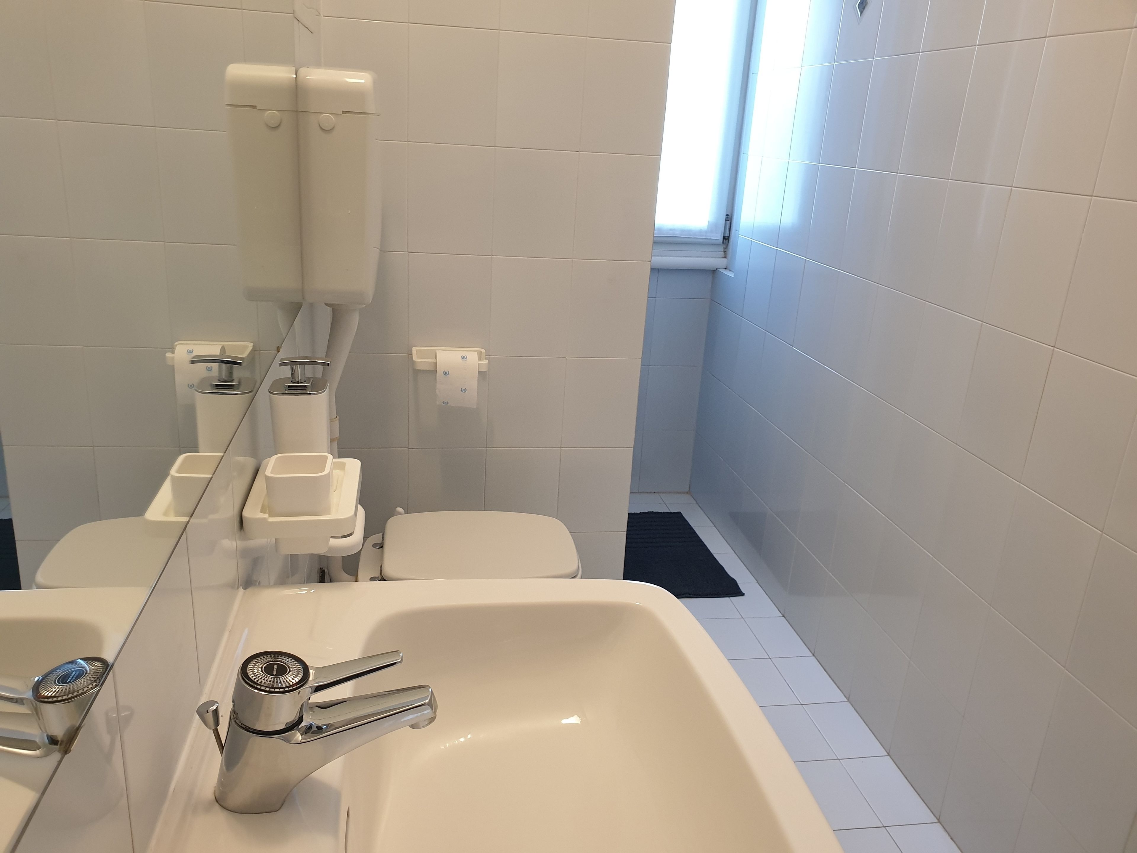 Een moderne badkamer met een witte wastafel, toilet en bidet.