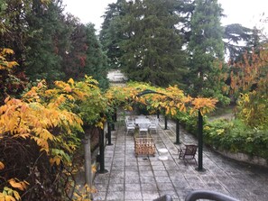 A paved pathway lined with benches and tables, surrounded by trees with autumn foliage. - B&B Villa al Parco (Sala Baganza)