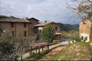 A rustic village with stone buildings, a dirt path, and a bench. - Agriturismo Le Selve (Comunanza)