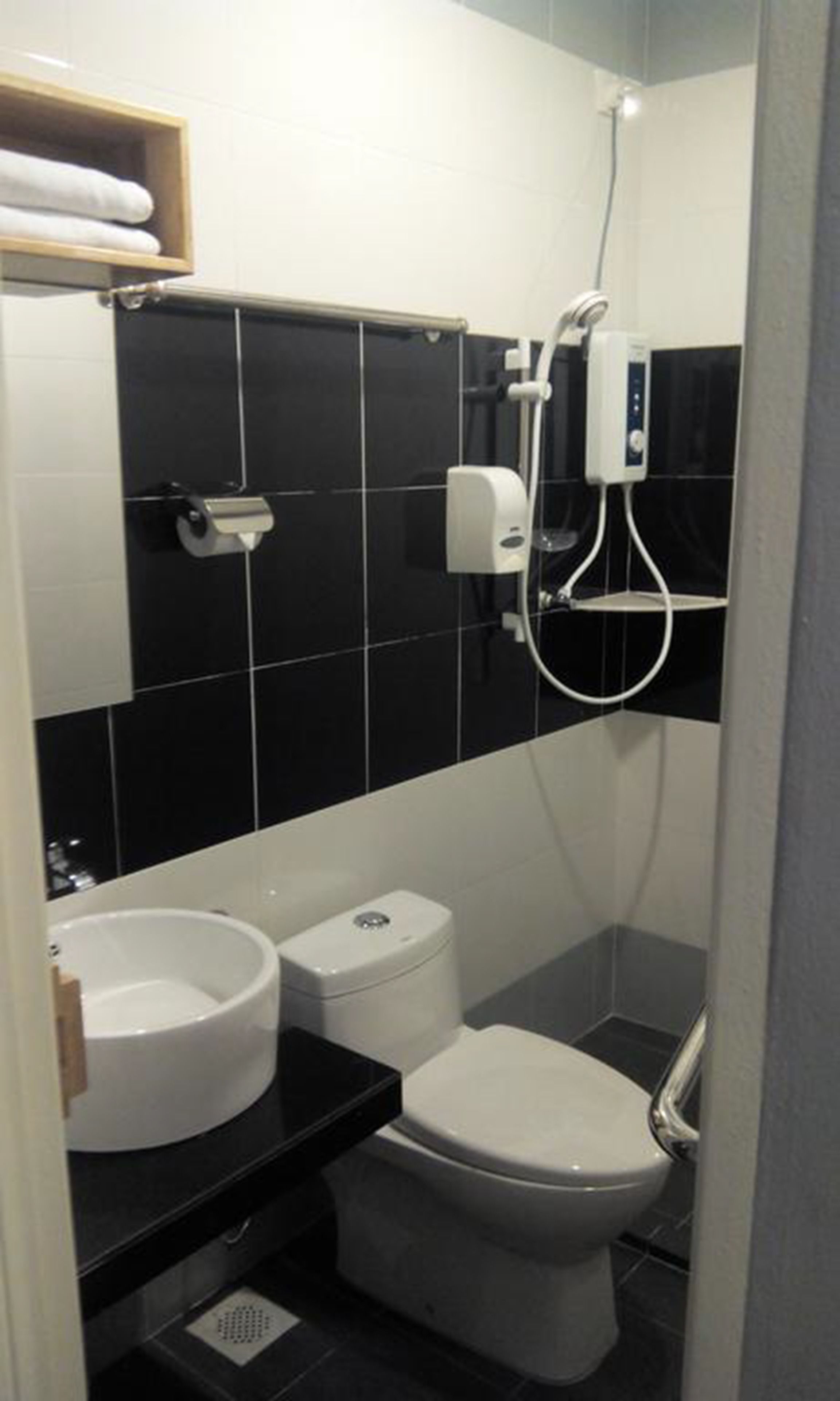 A compact bathroom with a toilet, a sink, and a shower unit.