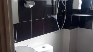 A modern bathroom with a black and white tiled backsplash, a white toilet, a sink, and a handheld showerhead.