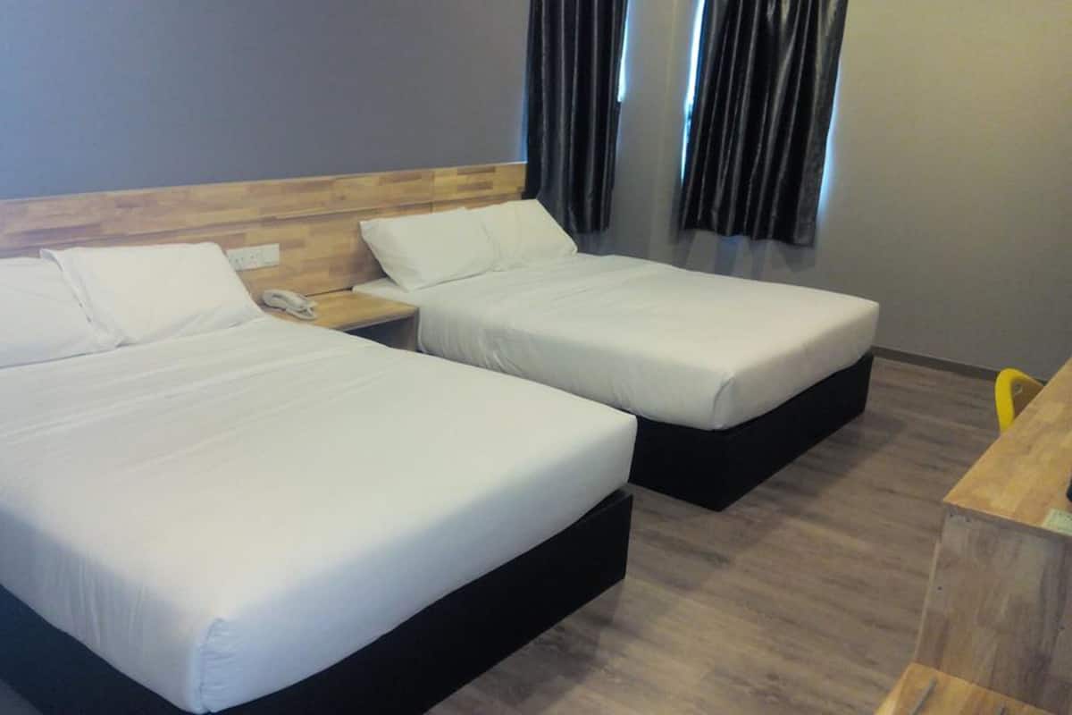 Habitación de hotel con dos camas individuales, cabecera de madera, mesita de noche con teléfono y escritorio de madera.