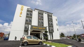 A hotel with a modern facade, a parking lot, and a small car parked in front.