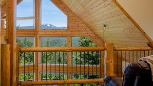 A wooden cabin with large windows offering mountain views. - Luxurious Chalet Retreat: Breathtaking Views, Hot Tub, BBQ, and Fireside Comfort (Crescent)