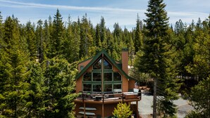 A cabin with a large glass front, wooden deck, and a forest backdrop. - Luxurious Chalet Retreat: Breathtaking Views, Hot Tub, BBQ, and Fireside Comfort (Crescent)
