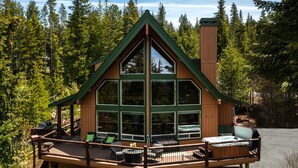 A cabin with a deck, large windows, and a hot tub. - Luxurious Chalet Retreat: Breathtaking Views, Hot Tub, BBQ, and Fireside Comfort (Crescent)