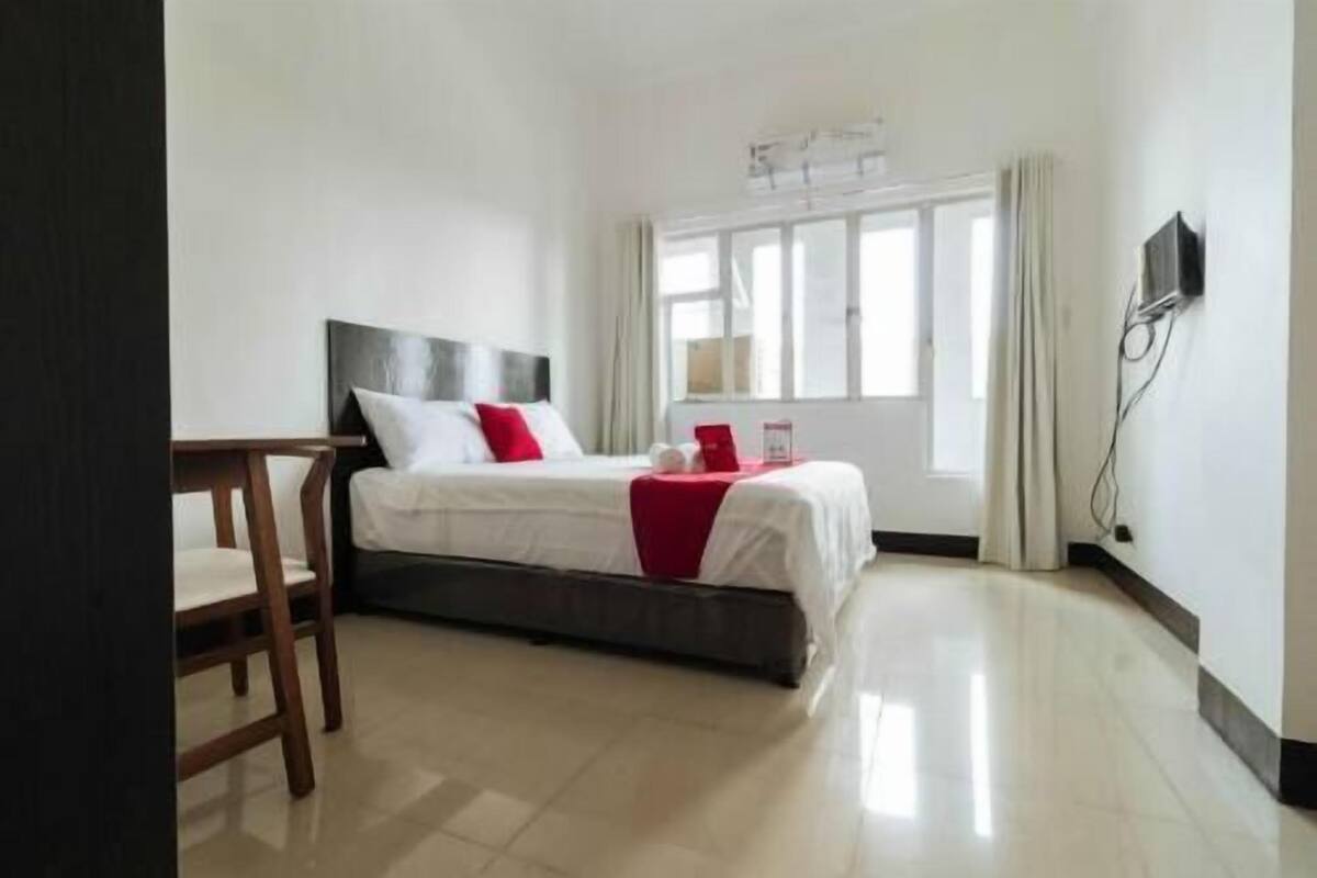 Habitación de hotel con cama, escritorio, ventana y televisor de pantalla plana montado en la pared.