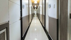 Um corredor comprido e estreito, com portas em ambos os lados, dando acesso a quartos individuais.