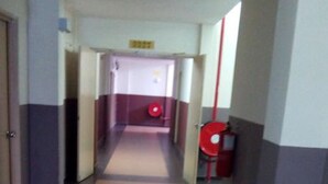 A corridor with a tiled floor, a red fire extinguisher on the right, and a door at the end. -  JQ Suria Hotel (Ipoh)