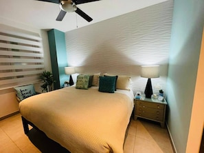 A bedroom with a bed, nightstands, a ceiling fan, and a wall with a textured pattern.