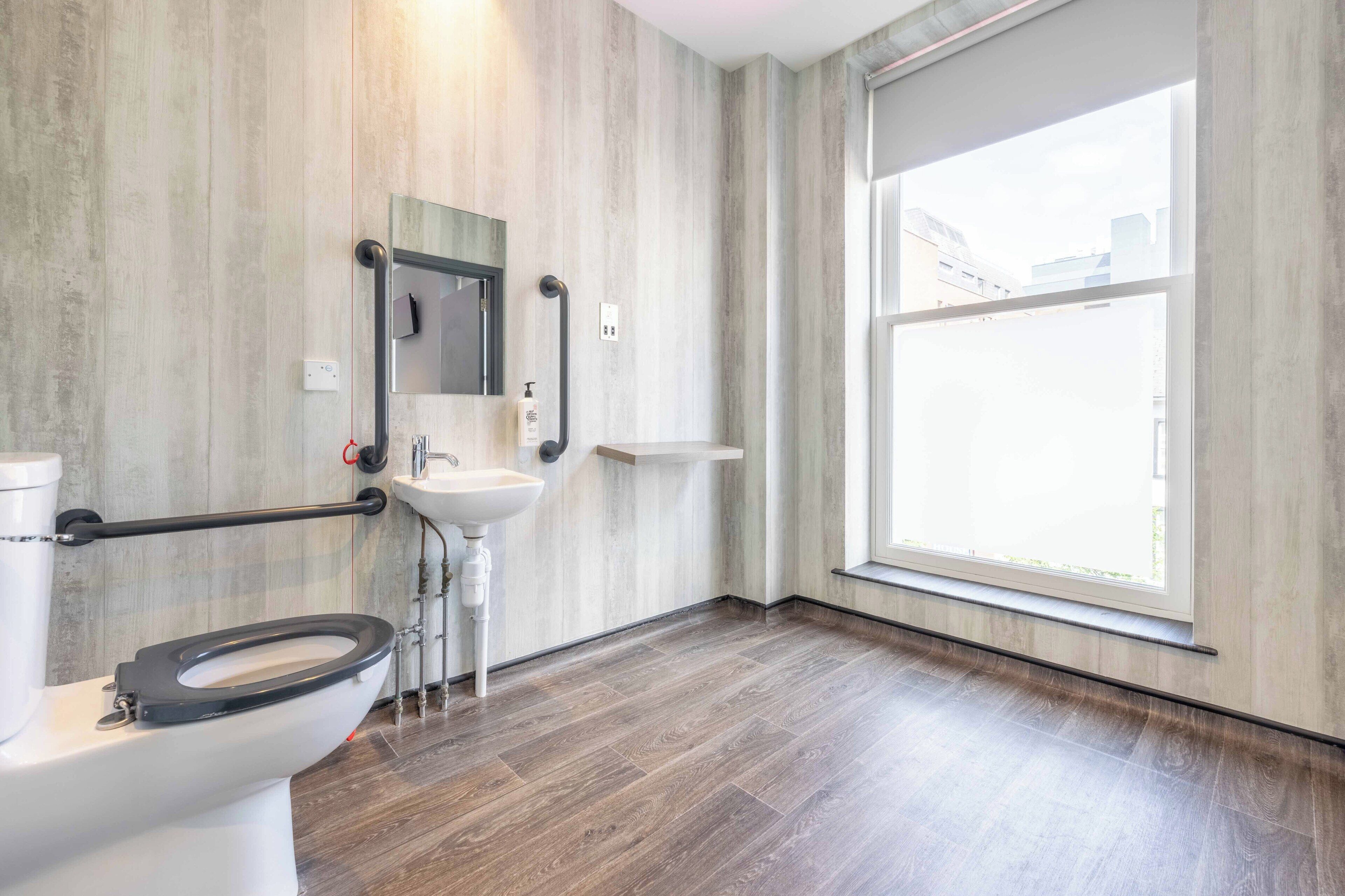 A modern bathroom with a toilet, sink, and large window.