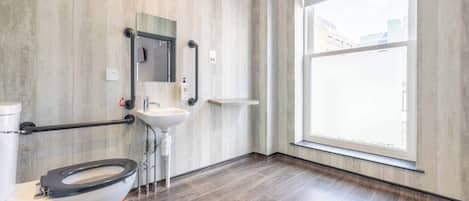 A modern bathroom with a toilet, sink, and large window.