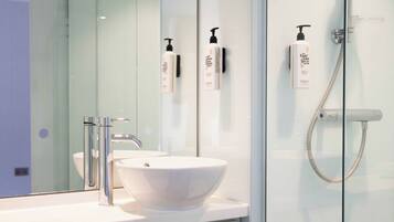 A modern bathroom with a white sink, chrome faucet, and a glass shower enclosure.