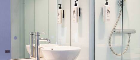A modern bathroom with a white sink, chrome faucet, and a glass shower enclosure.