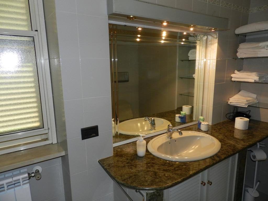 Baño con lavamanos, espejo y toallero.