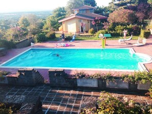 A rectangular swimming pool with a clear blue water, surrounded by a brick deck and stone walls.