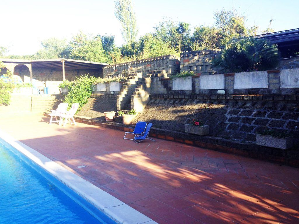 Une piscine avec un mur en briques et des marches menant à un espace abrité.