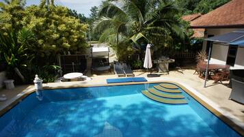 A swimming pool with a dolphin design, surrounded by palm trees and a covered patio area.