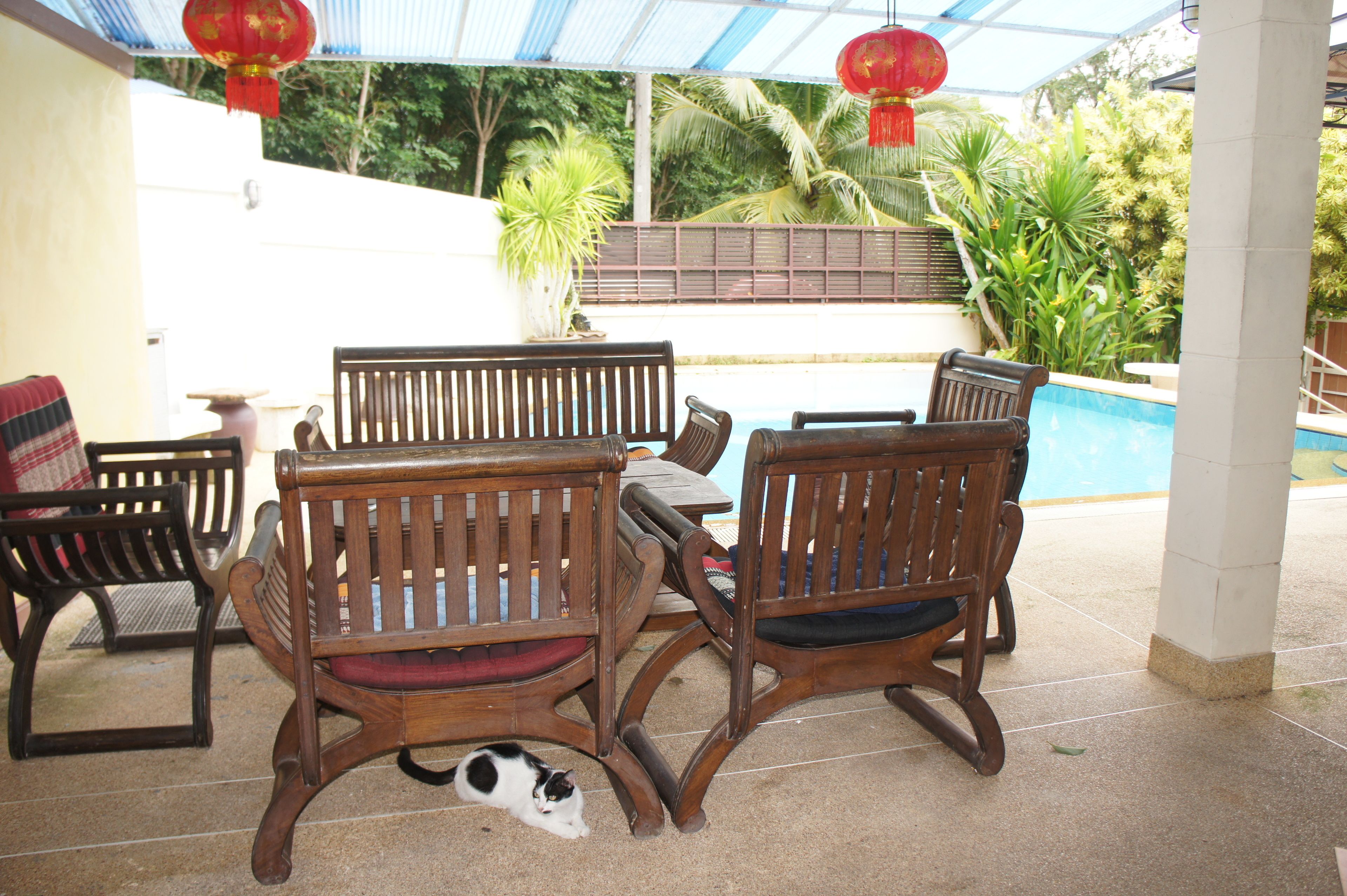 Un patio con mobiliario de madera y una piscina.