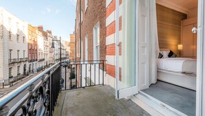 Un balcon doté d’une rambarde en métal, donnant sur une rue bordée d’immeubles.