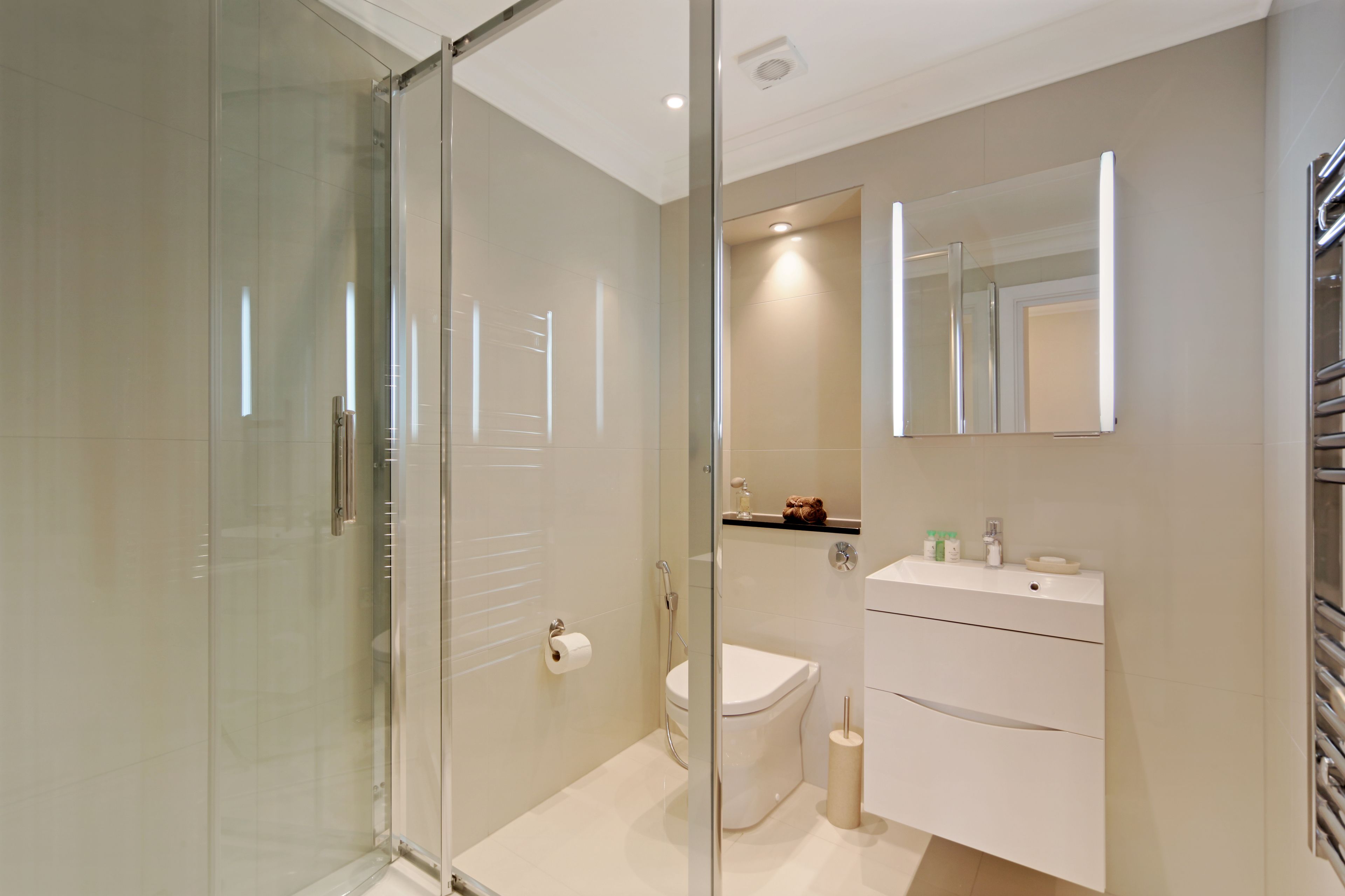 Un baño moderno con cabina de ducha de vidrio, inodoro y tocador con espejo.