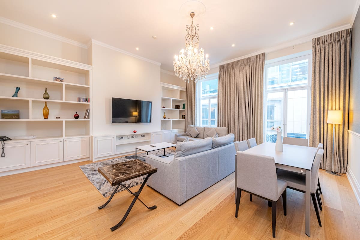 A modern living room with a grey sofa, a coffee table, a TV, and a chandelier.