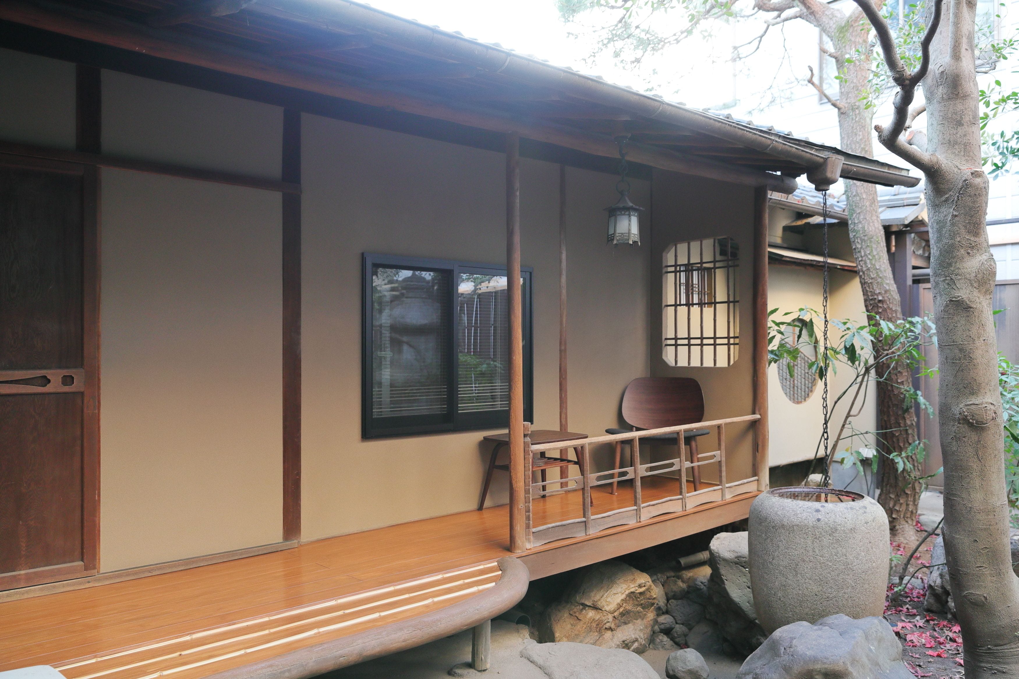 A traditional Japanese building with a wooden deck, a stone lantern, and a potted plant.