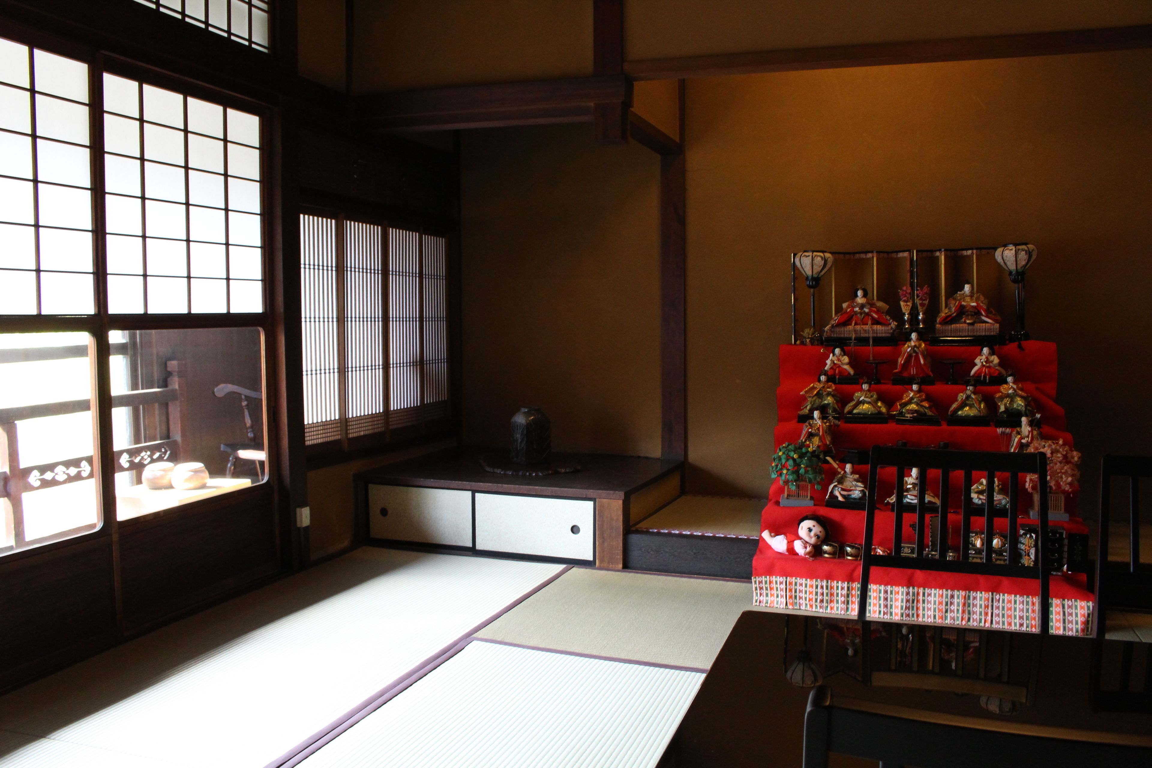 A traditional Japanese room with tatami flooring, sliding doors, and a red altar with religious statues.