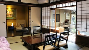 Ein traditioneller japanischer Raum mit Tatami-Bodenbelag, einem niedrigen Tisch und Holzstühlen.