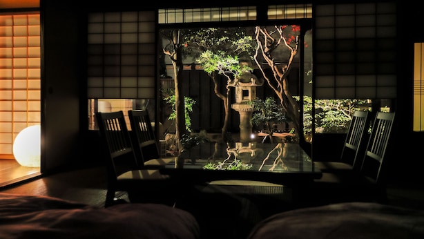 Ein traditioneller japanischer Raum mit Tatami-Boden, einem niedrigen Tisch und Sesseln.