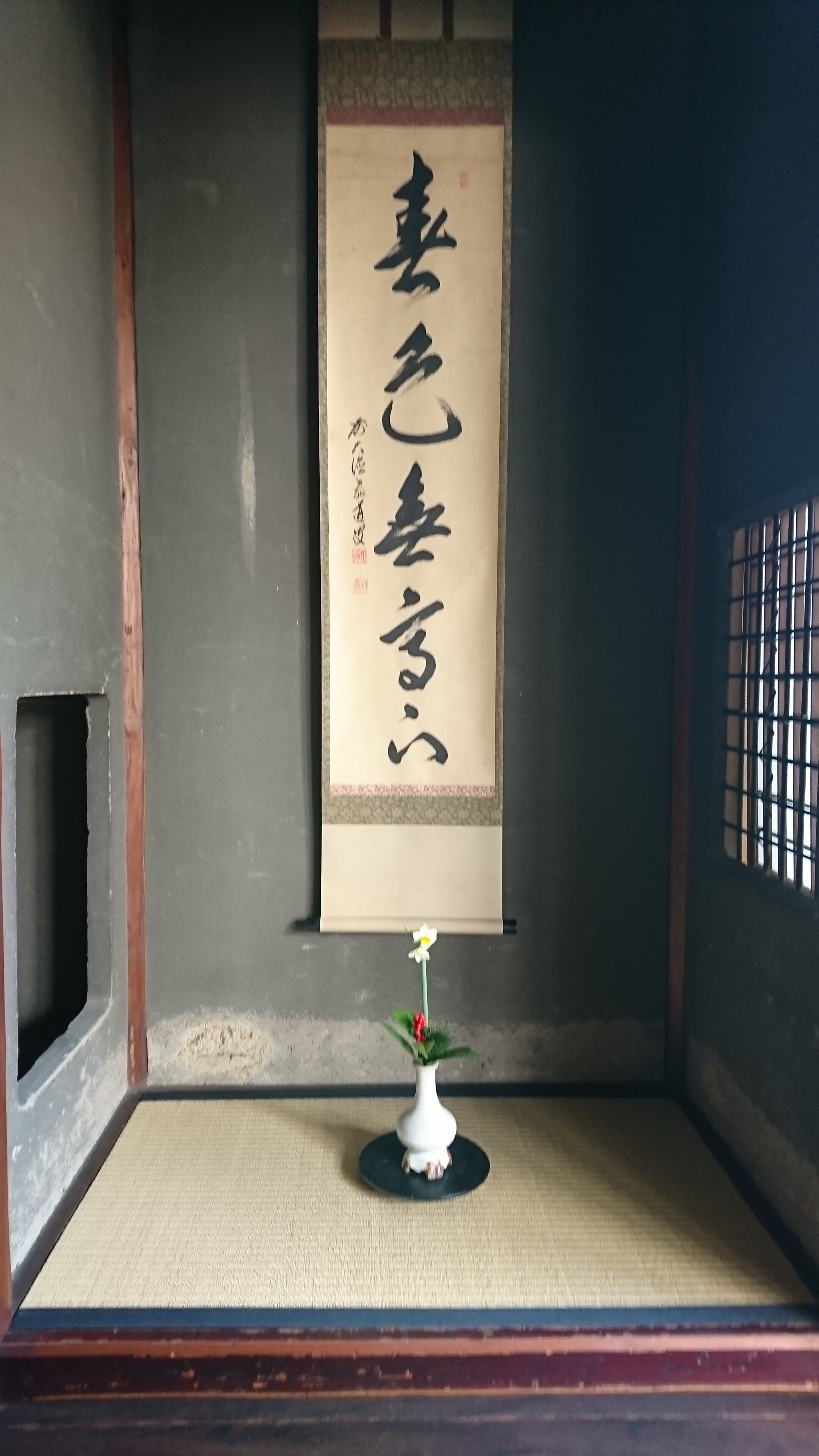 Une pièce de style japonais traditionnel, avec un sol recouvert de tatamis, un paravent shoji et un rouleau calligraphié suspendu au mur.