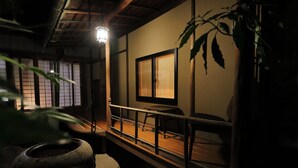 Ein traditioneller japanischer Raum mit Tatami-Boden, einem niedrigen Tisch, einer Schiebetür und einer hängenden Leuchte.