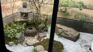 Ein traditioneller japanischer Garten mit Steintorii, Moos, Felsen und einem kleinen Teich.