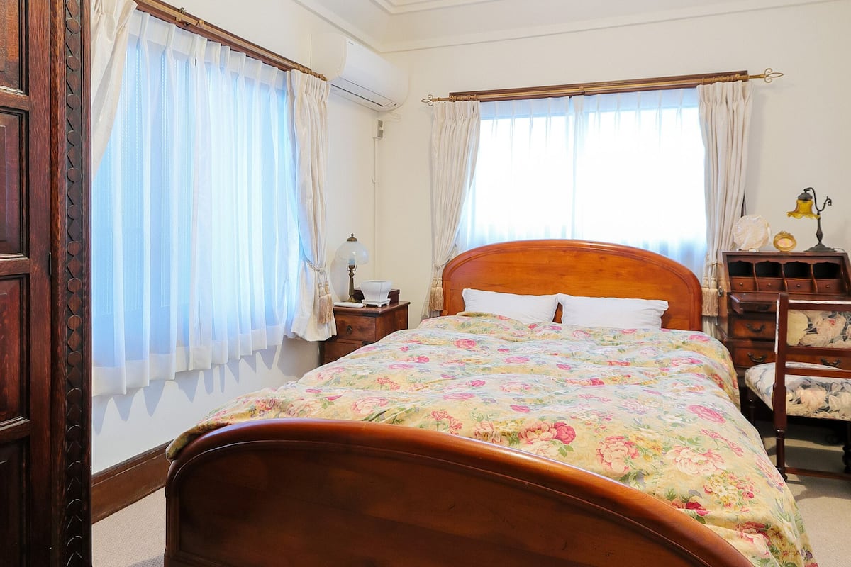 Un dormitorio con una cama de madera, una mesita de noche, una silla y un aparador.