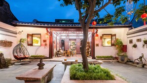 A traditional courtyard with a stone bench, a hanging chair, and a potted plant. - Chaozhou Manju Inn (Chaozhou)