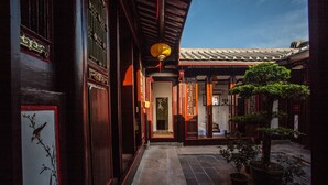 A traditional courtyard with wooden architecture, a tiled floor, and potted plants. - Chaozhou Manju Inn (Chaozhou)