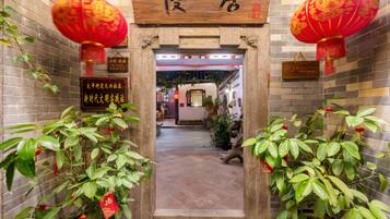A traditional Chinese entrance with red lanterns, potted plants, and a signboard.